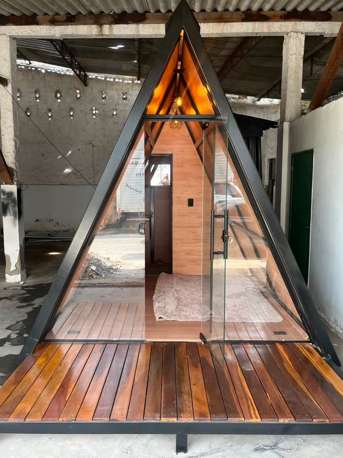 Fachada frontal do chalé A-frame com porta em vidro Blindex e deck em madeira de lei