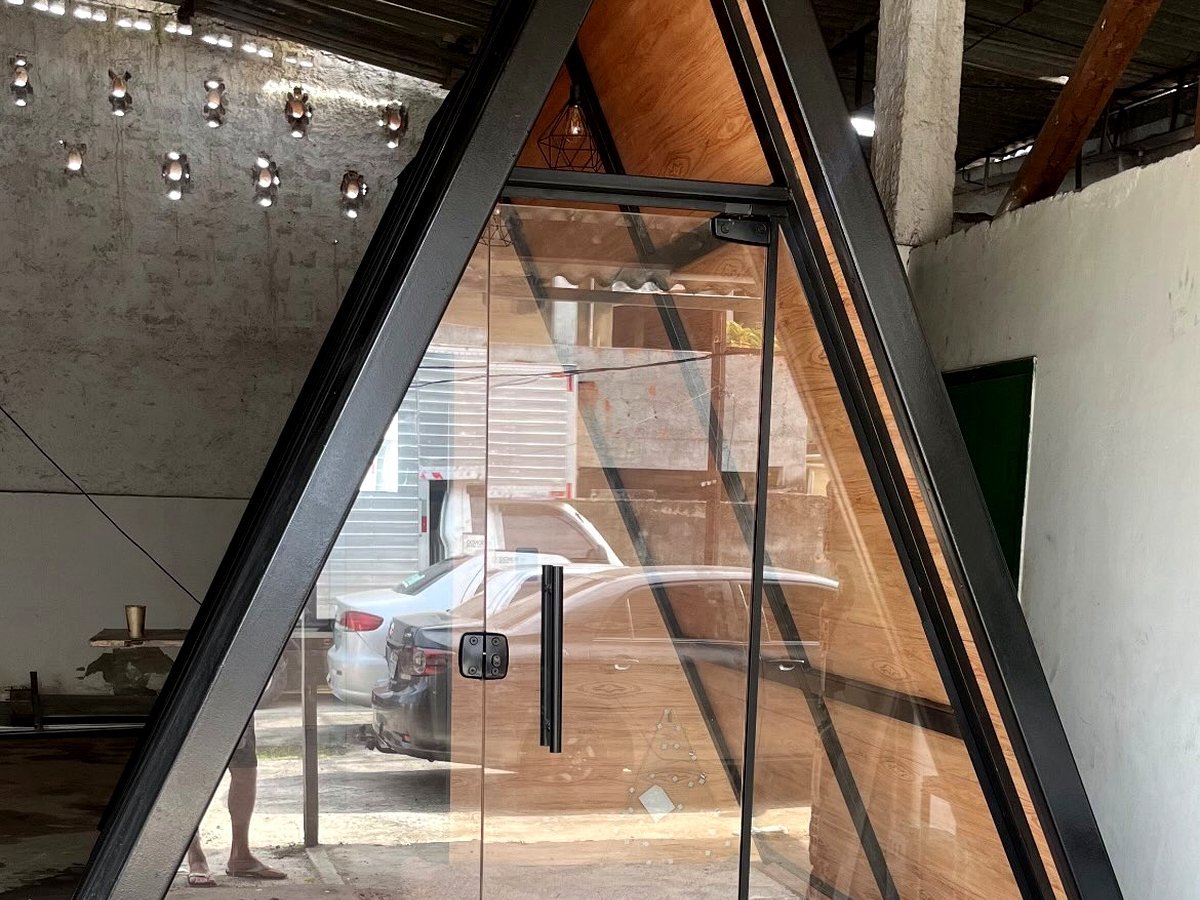 Chalé A-frame visto de frente, com fachada em vidro e deck em madeira de lei